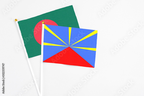 Reunion and Bangladesh stick flags on white background. High quality fabric, miniature national flag. Peaceful global concept.White floor for copy space.