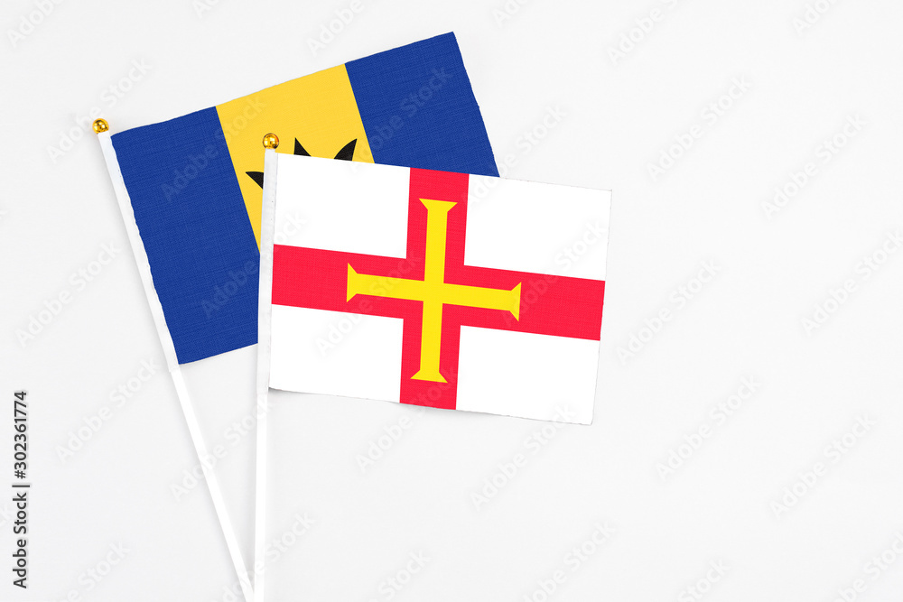 Guernsey and Barbados stick flags on white background. High quality fabric, miniature national flag. Peaceful global concept.White floor for copy space.