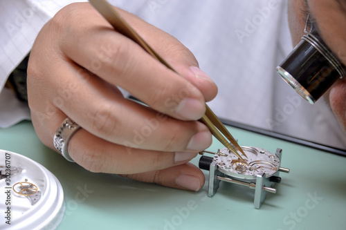 Photography Watchmaker picked up the tiny escape wheel part very carefully to mainplate
