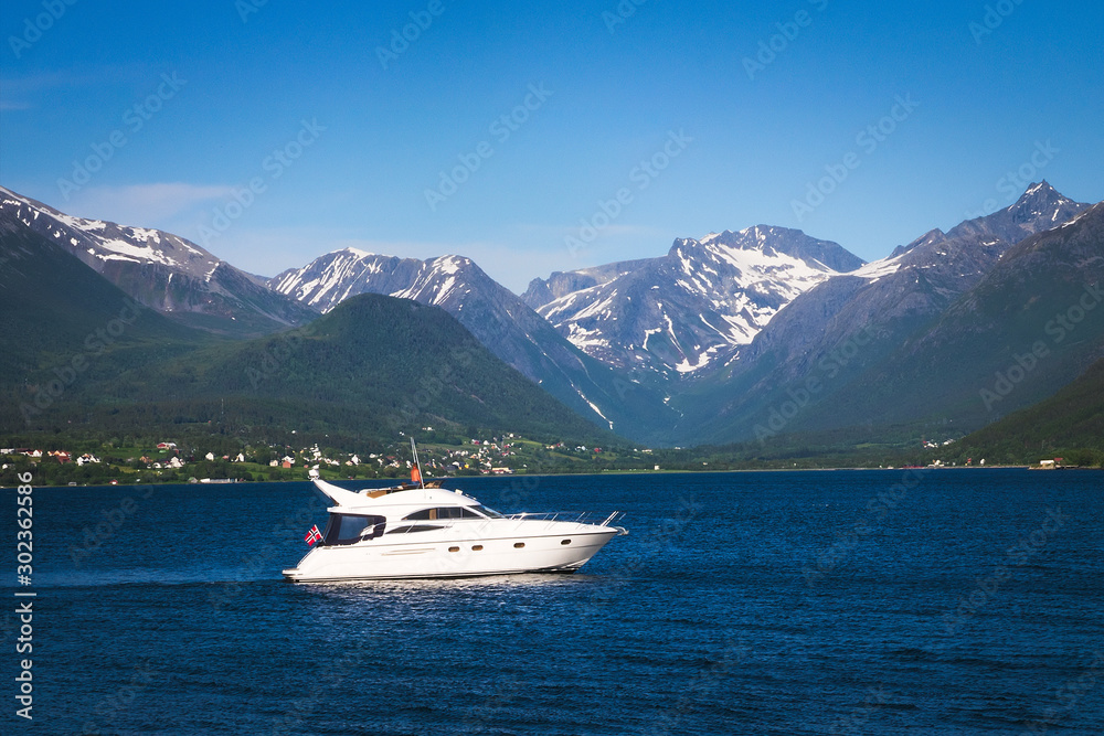 Beautiful mountains and fjord in Norway with a white pleasure boat on the calm blue water on a sunny day. Beautiful mountains and fjord in Norway with a white pleasure boat on the calm blue water on a sunny day.
