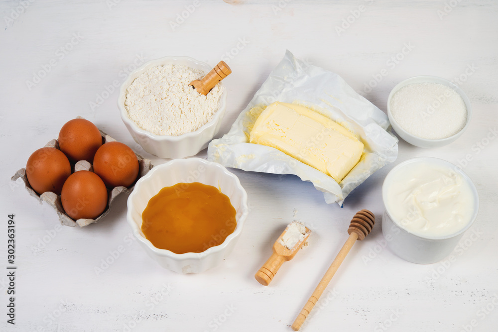 The ingredients for the honey cake are laid out on a white table in the middle. Horizontal orientation.