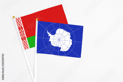 Antarctica and Belarus stick flags on white background. High quality fabric, miniature national flag. Peaceful global concept.White floor for copy space. photo