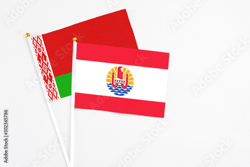 French Polynesia and Belarus stick flags on white background. High quality fabric, miniature national flag. Peaceful global concept.White floor for copy space. photo