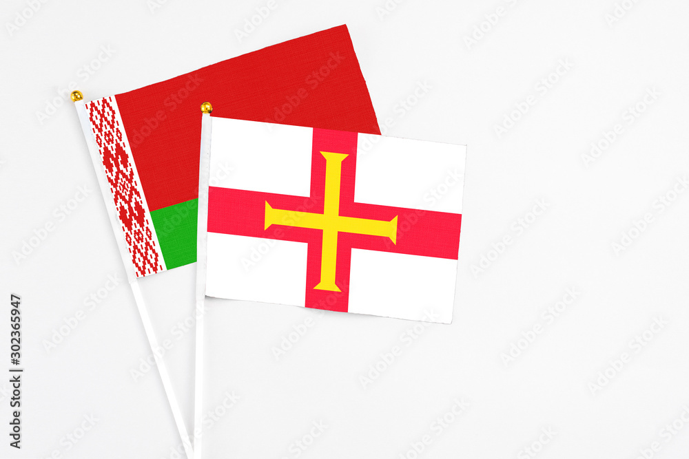 Guernsey and Belarus stick flags on white background. High quality fabric, miniature national flag. Peaceful global concept.White floor for copy space.