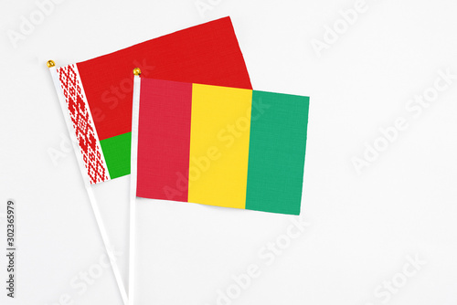 Guinea and Belarus stick flags on white background. High quality fabric, miniature national flag. Peaceful global concept.White floor for copy space. photo