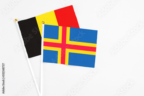 Aland Islands and Belgium stick flags on white background. High quality fabric, miniature national flag. Peaceful global concept.White floor for copy space. photo