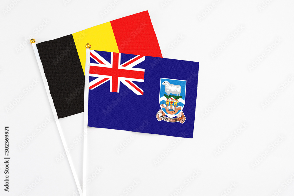 Fototapeta premium Falkland Islands and Belgium stick flags on white background. High quality fabric, miniature national flag. Peaceful global concept.White floor for copy space.