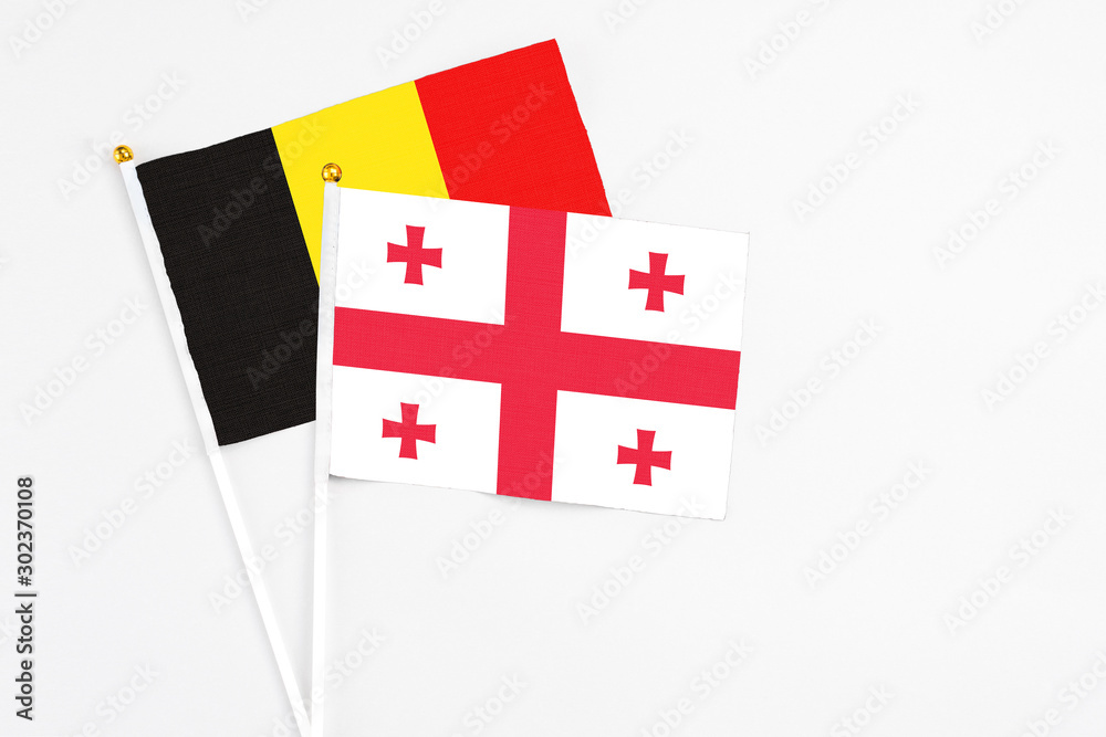 Georgia and Belgium stick flags on white background. High quality fabric, miniature national flag. Peaceful global concept.White floor for copy space.