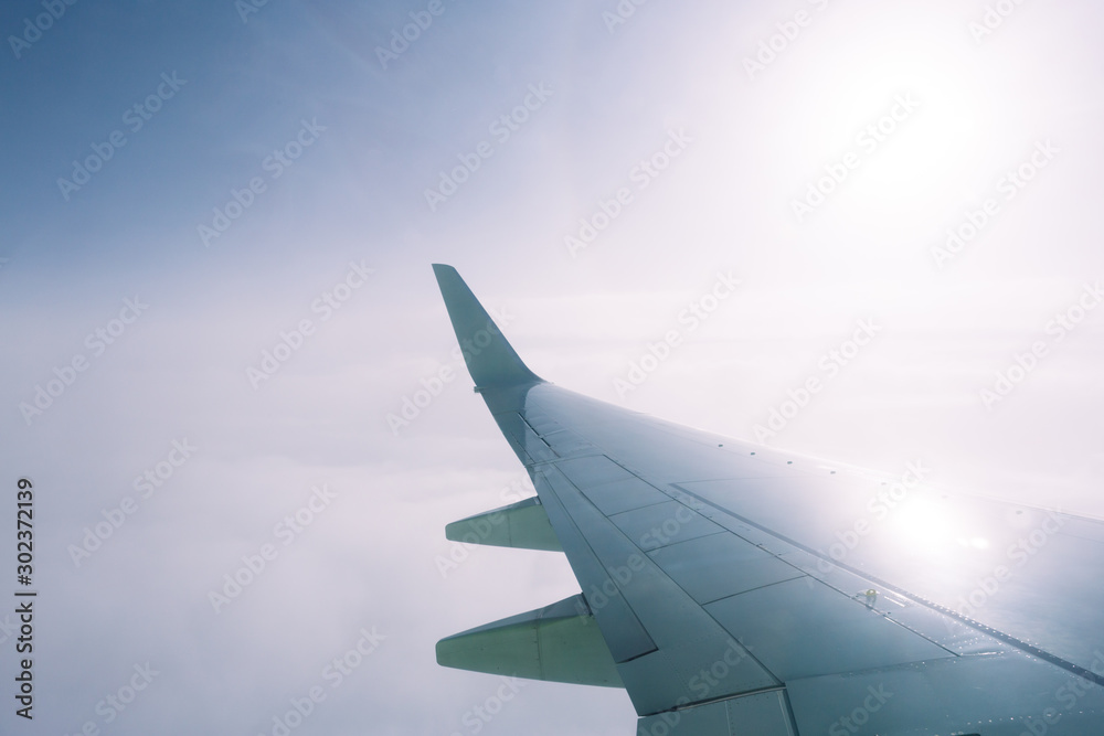 Fototapeta premium Wing of an airplane flying above the clouds