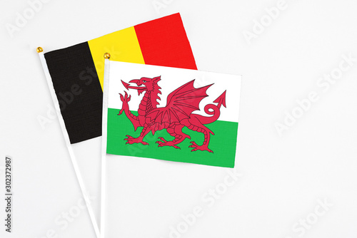 Wales and Belgium stick flags on white background. High quality fabric, miniature national flag. Peaceful global concept.White floor for copy space.