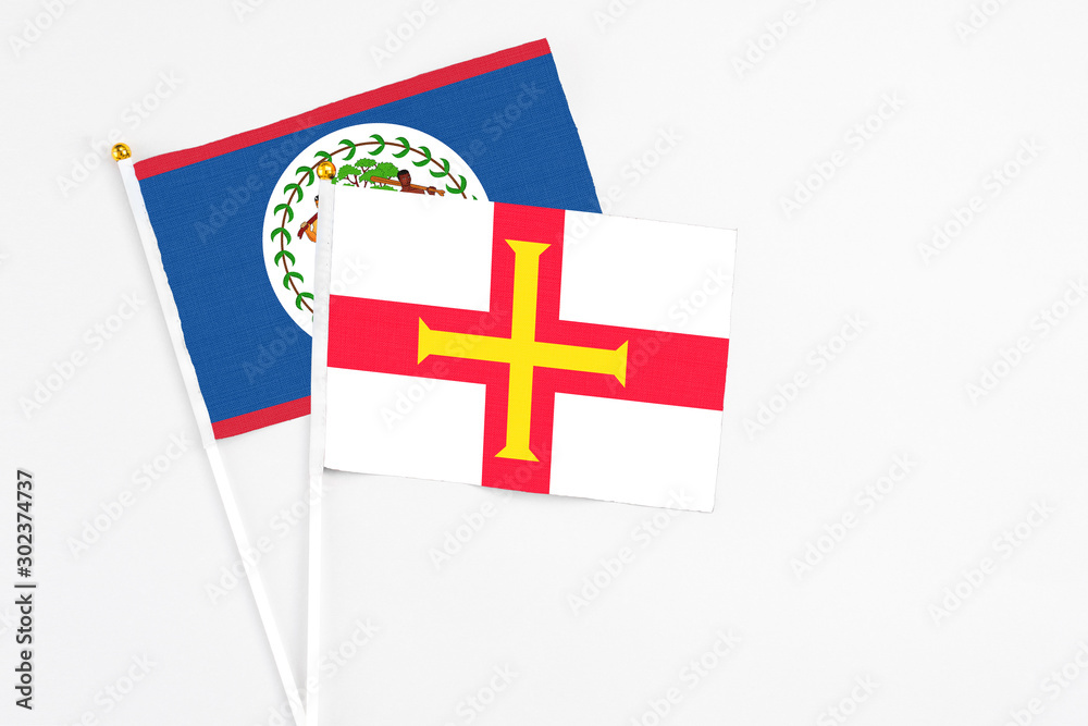 Guernsey and Belize stick flags on white background. High quality fabric, miniature national flag. Peaceful global concept.White floor for copy space.