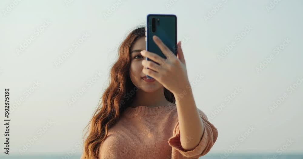 Asian beautiful woman using smartphone at sea background. Woman using mobile with attractive smile. Lifestyle, Technology and travel concept. Asian beautiful woman using smartphone at sea background. Woman using mobile with attractive smile. Lifestyle, Technology and travel concept.