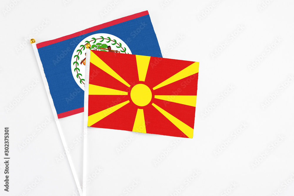 Macedonia and Belize stick flags on white background. High quality fabric, miniature national flag. Peaceful global concept.White floor for copy space.