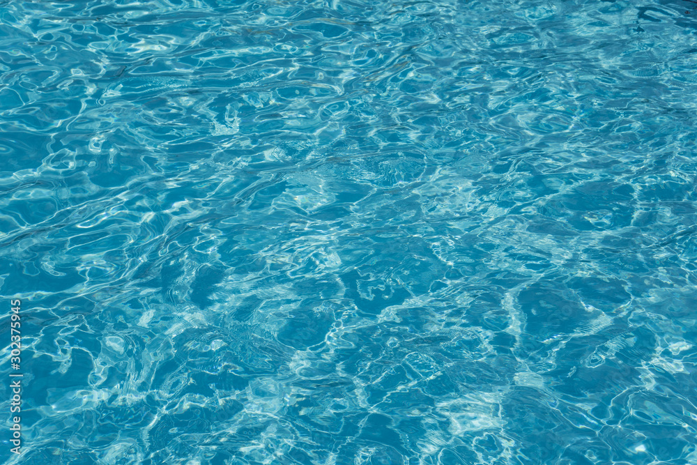 The texture of the crystal clear water in the pool. Safe swimming. Water in bright light The texture of the crystal clear water in the pool. Safe swimming. Water in bright light