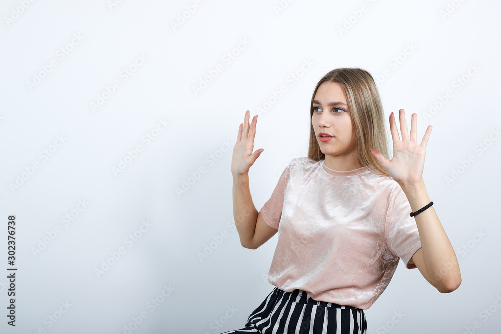 Portrait of serious young woman in casual clothes showing stop gesture with palm isolated on white wall background in studio. People sincere emotions lifestyle concept.