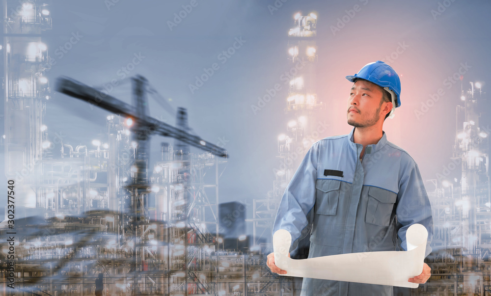 Engineers holding blue prints on their hands and standing in front of the power plant.