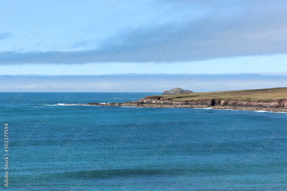 peaceful waves on the ocean, in the distance cliffs and hills on the island peaceful waves on the ocean, in the distance cliffs and hills on the island