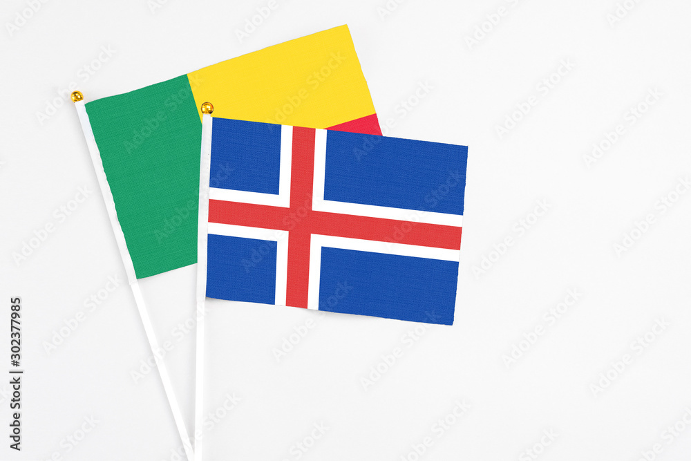 Iceland and Benin stick flags on white background. High quality fabric, miniature national flag. Peaceful global concept.White floor for copy space.