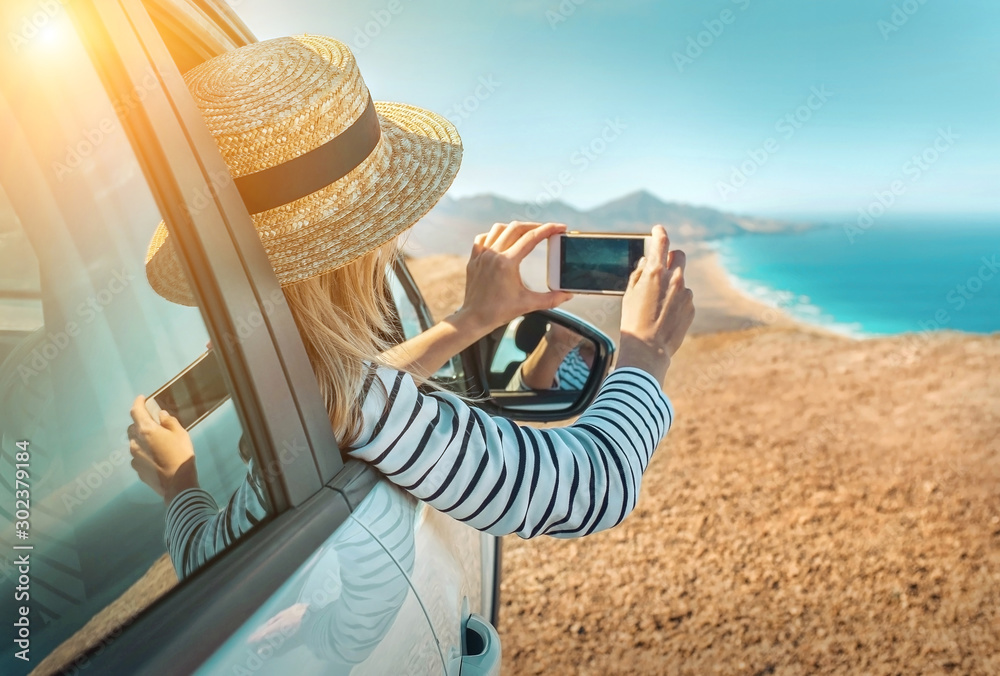 Fototapeta premium Happiness young woman sitting in white car and shoot with her ph