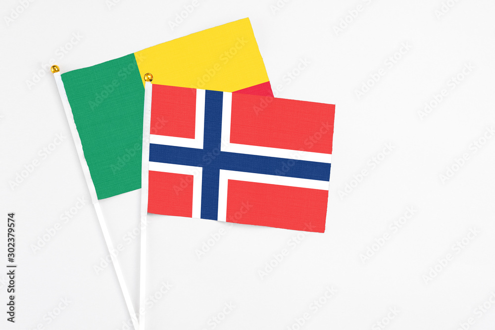 Norway and Benin stick flags on white background. High quality fabric, miniature national flag. Peaceful global concept.White floor for copy space.