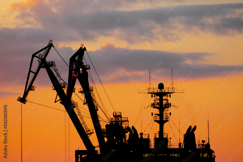 Petroleum oil mining by the sunset construction with cranes, harbor, cargo docks, port