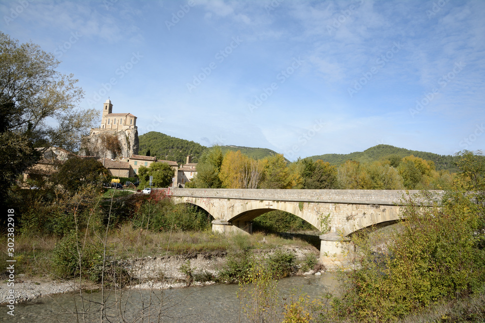 A village of Provence named Pierrelongue. A chapel perched on a rock, a river, an old stone bridge, a blue sky. South of France.
