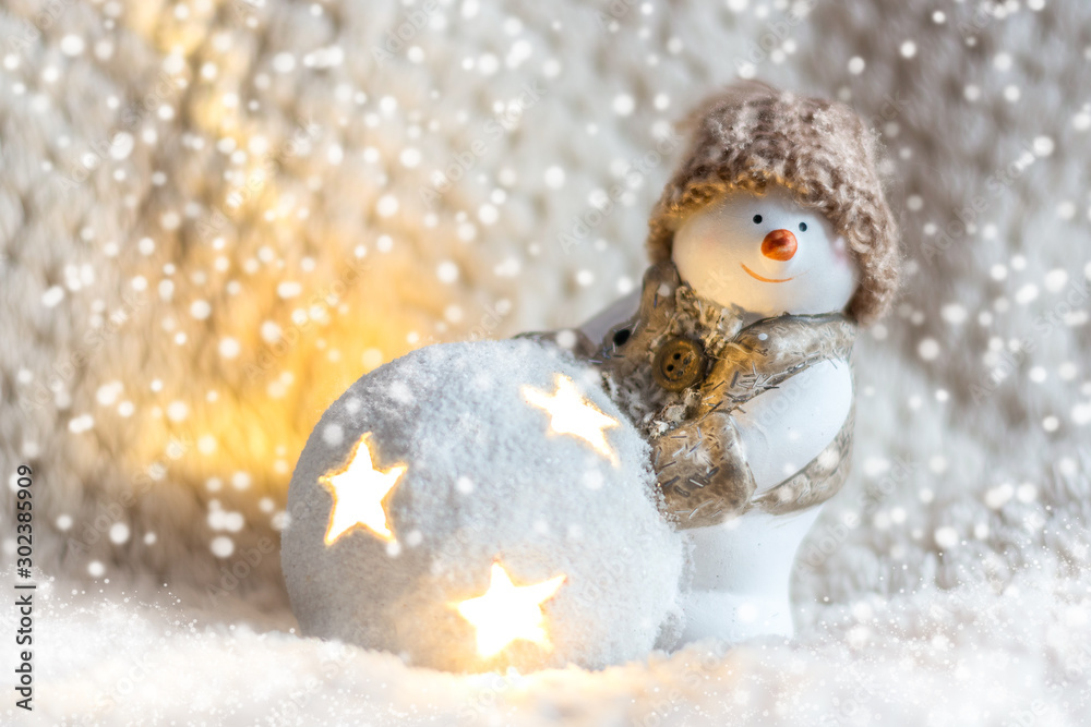 Obraz premium Toy snowman in a knitted hat, with a luminous ball close up on a white background, front view. New Year and Christmas background for greetings, banner, postcard, advertisement, Copy space, place for t
