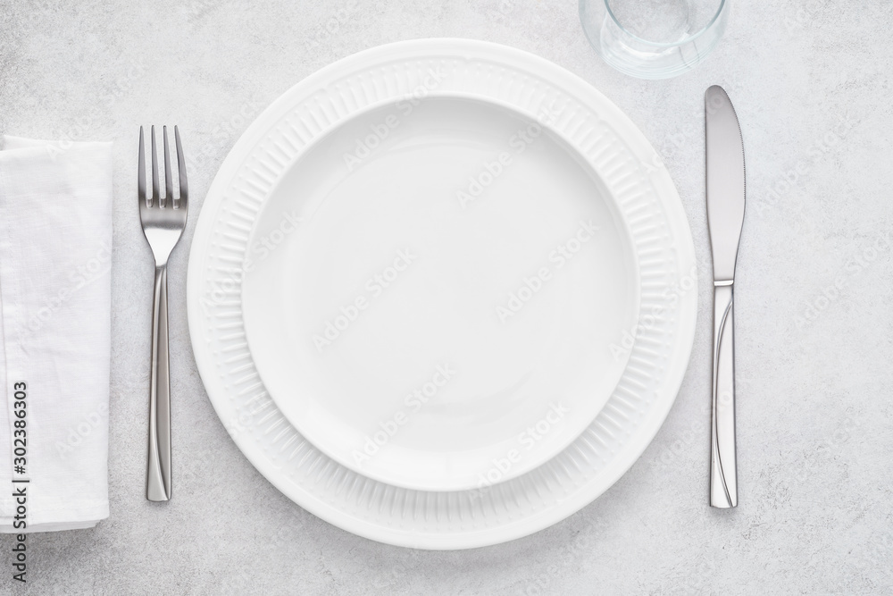 Table setting with white plates, glass, napkin, fork and knife.