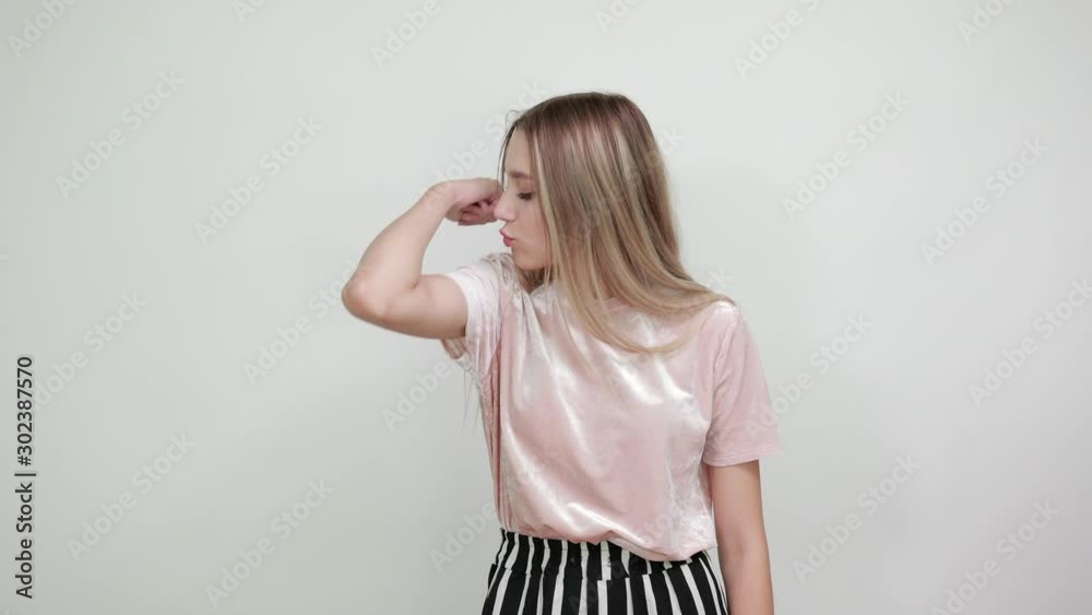 Attractive caucasian young funny woman wearing pretty shirt looking on hands, trying her muscles and kiss on isolated white background Attractive caucasian young funny woman wearing pretty shirt looking on hands, trying her muscles and kiss on isolated white background
