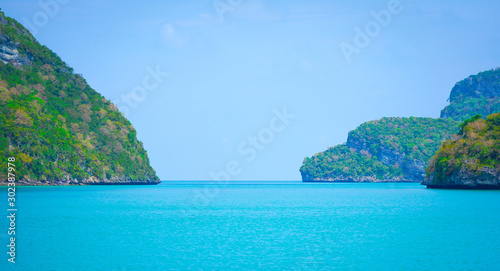 Islands green lush tropical island in a blue and turquoise sea background © arwiyada