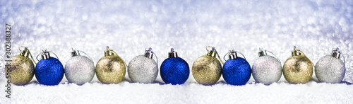 Row of christmas balls in the snow on the background sparkles. Good New Year spirit