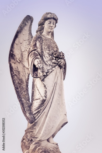 close up image of an angel figurine against a pale sky background.