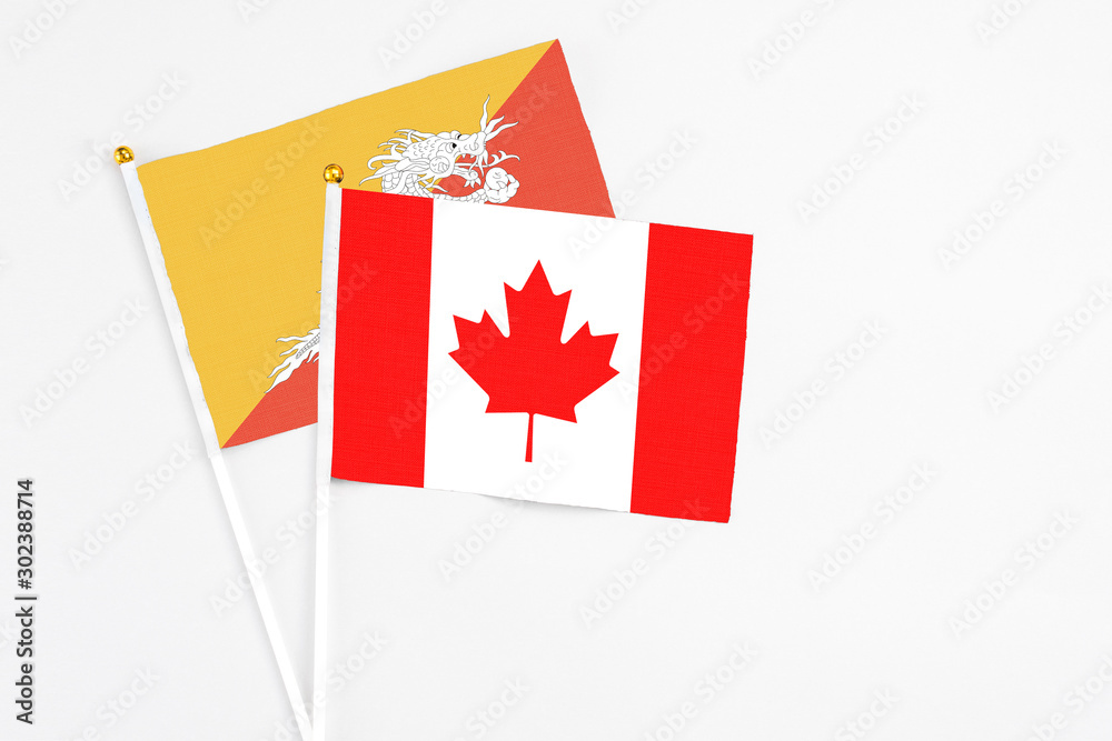 Canada and Bhutan stick flags on white background. High quality fabric, miniature national flag. Peaceful global concept.White floor for copy space. Canada and Bhutan stick flags on white background. High quality fabric, miniature national flag. Peaceful global concept.White floor for copy space.