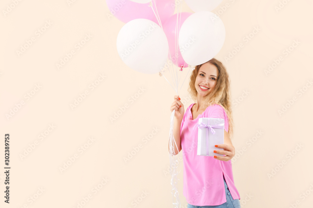 Beautiful young woman with balloons and gift on color background Beautiful young woman with balloons and gift on color background