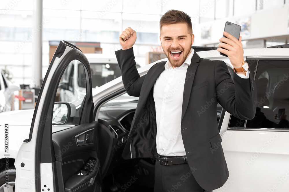 Happy male buyer near new car in salon Happy male buyer near new car in salon