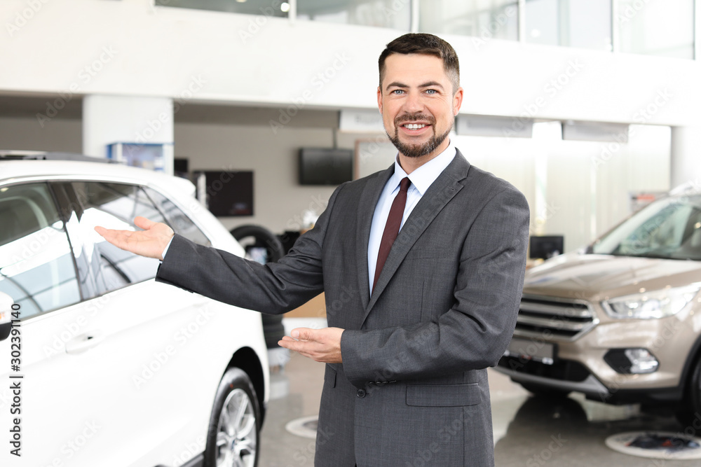 Salesman near car in modern salon Salesman near car in modern salon