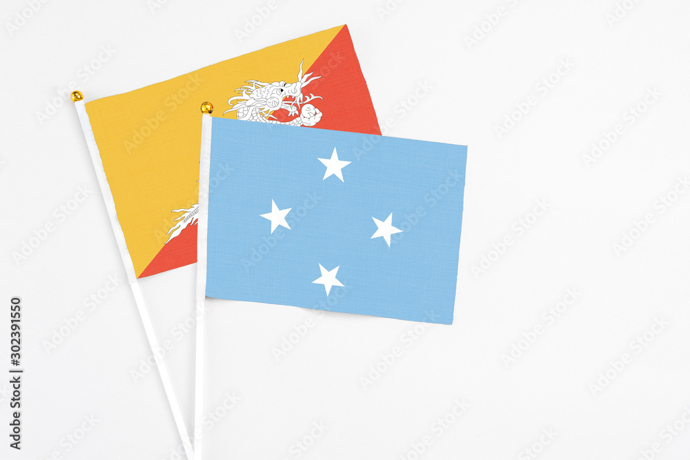 Micronesia and Bhutan stick flags on white background. High quality fabric, miniature national flag. Peaceful global concept.White floor for copy space. Micronesia and Bhutan stick flags on white background. High quality fabric, miniature national flag. Peaceful global concept.White floor for copy space.
