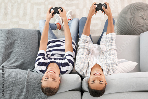 Teenager boys playing video games at home, top view