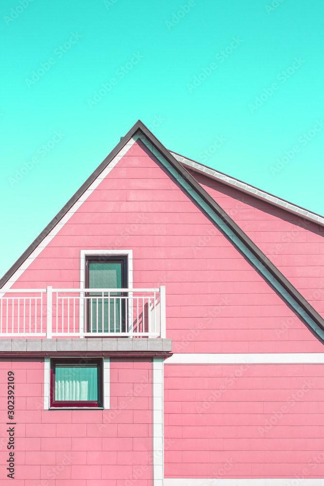 Pink minimalistic house architecture with balcony and cyan sky above roof
