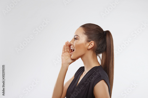 Beautiful young woman over isolated background shouting and screaming loud to side with hand on mouth. Communication concept