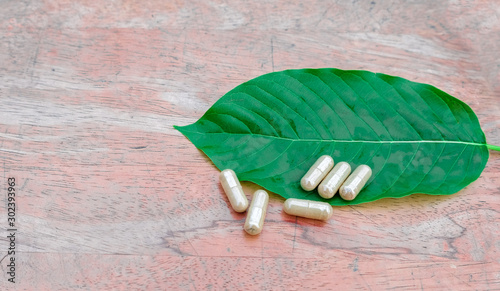 capsule on kratom leaf (Mitragyna speciosa) Mitragynine on wooden ,Drugs and Narcotics,Thai herbal which encourage health photo