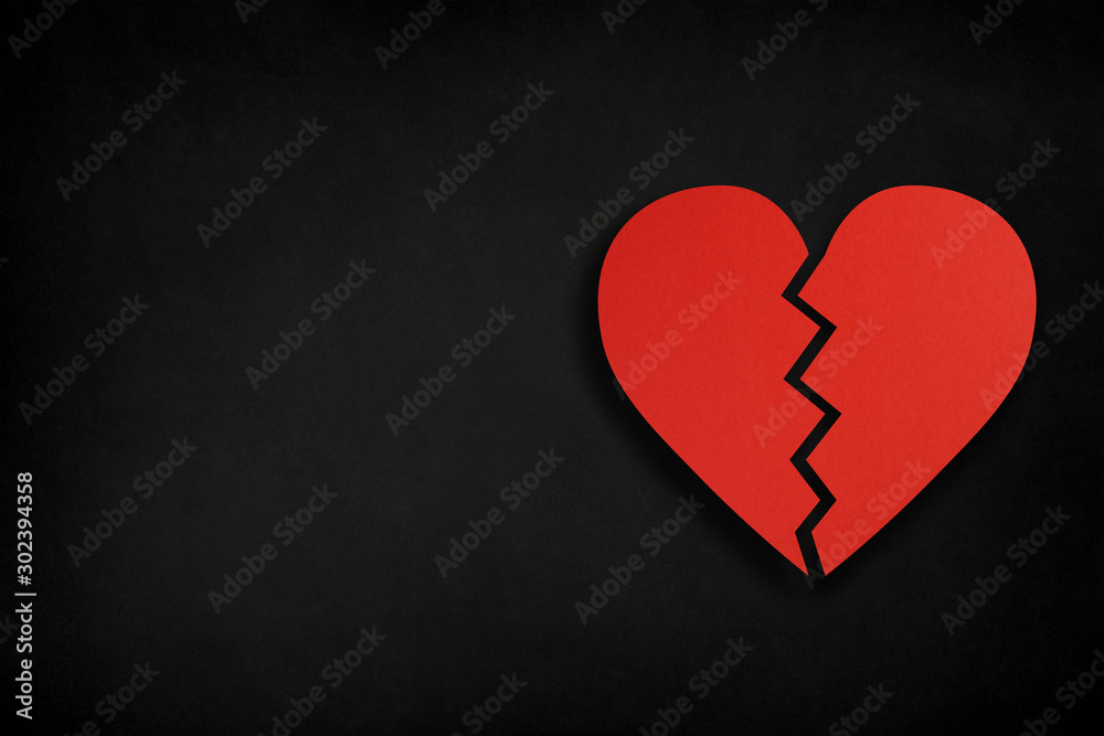 Broken heart shape made from cut paper with copy space on black background Broken heart shape made from cut paper with copy space on black background