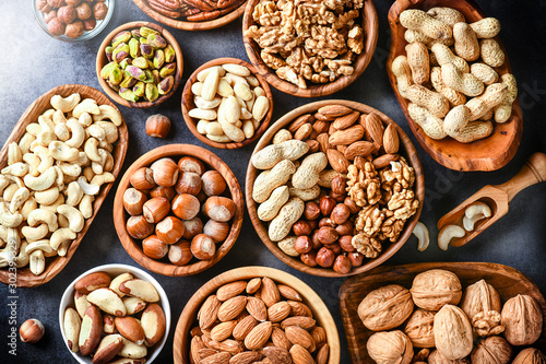 A variety of nuts in wooden bowls from top view. Walnuts, cashew, almond, pistachio, pecan, hazelnut, macadamia and peanut mix food selection.