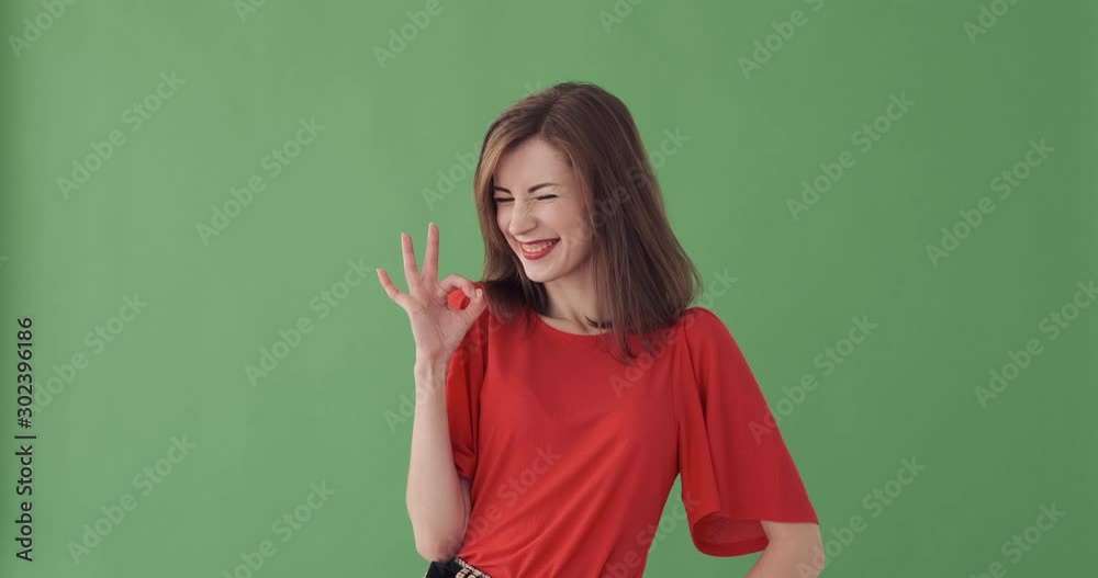 Happy young woman giving ok gesture over green background Happy young woman giving ok gesture over green background