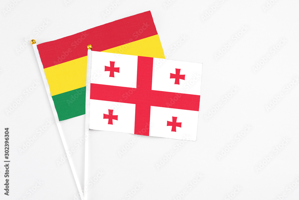 Georgia and Bolivia stick flags on white background. High quality fabric, miniature national flag. Peaceful global concept.White floor for copy space.