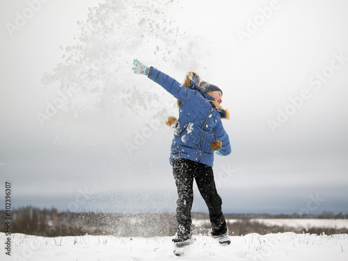 Happy child jumping. Lots of flying snow. Enjoy outdoor games in winter