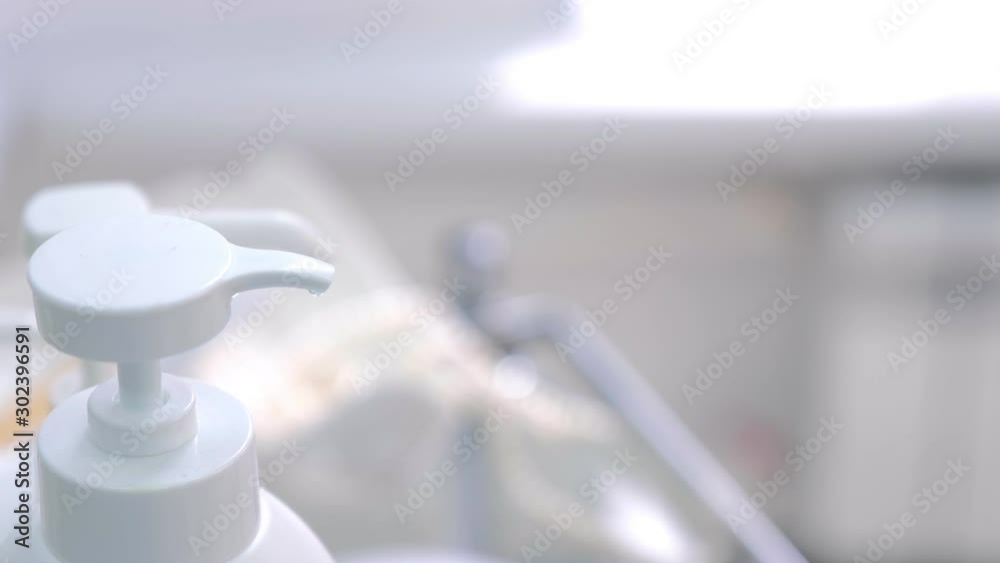 Doctor woman in gloves squeezes face tonic from dispenser on cotton pad, hands closeup. Cosmetologist is taking cleaning liquid for procedure. Beauty procedure in clinic.