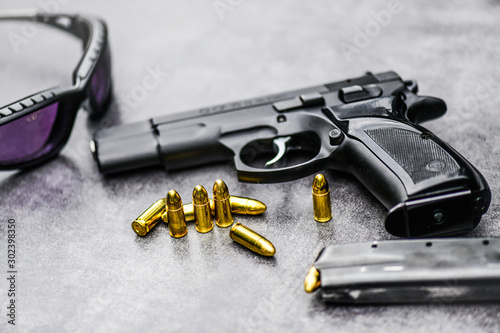 Gun with ammunition on stone background. 9 mm pistol gun weapon and bullets at table.