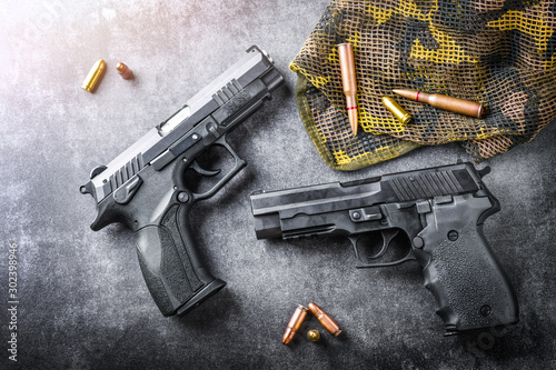 Hand guns on dark stone table top view. ammunition or bullets at black background. photo