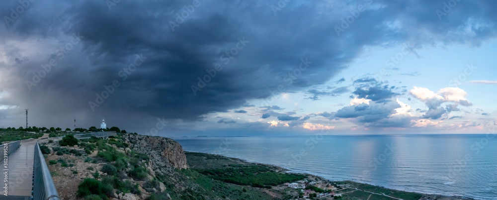 Lighthouse of Santa Pola built in 1858 near Alicante, Spain. Rain clouds and sea view.